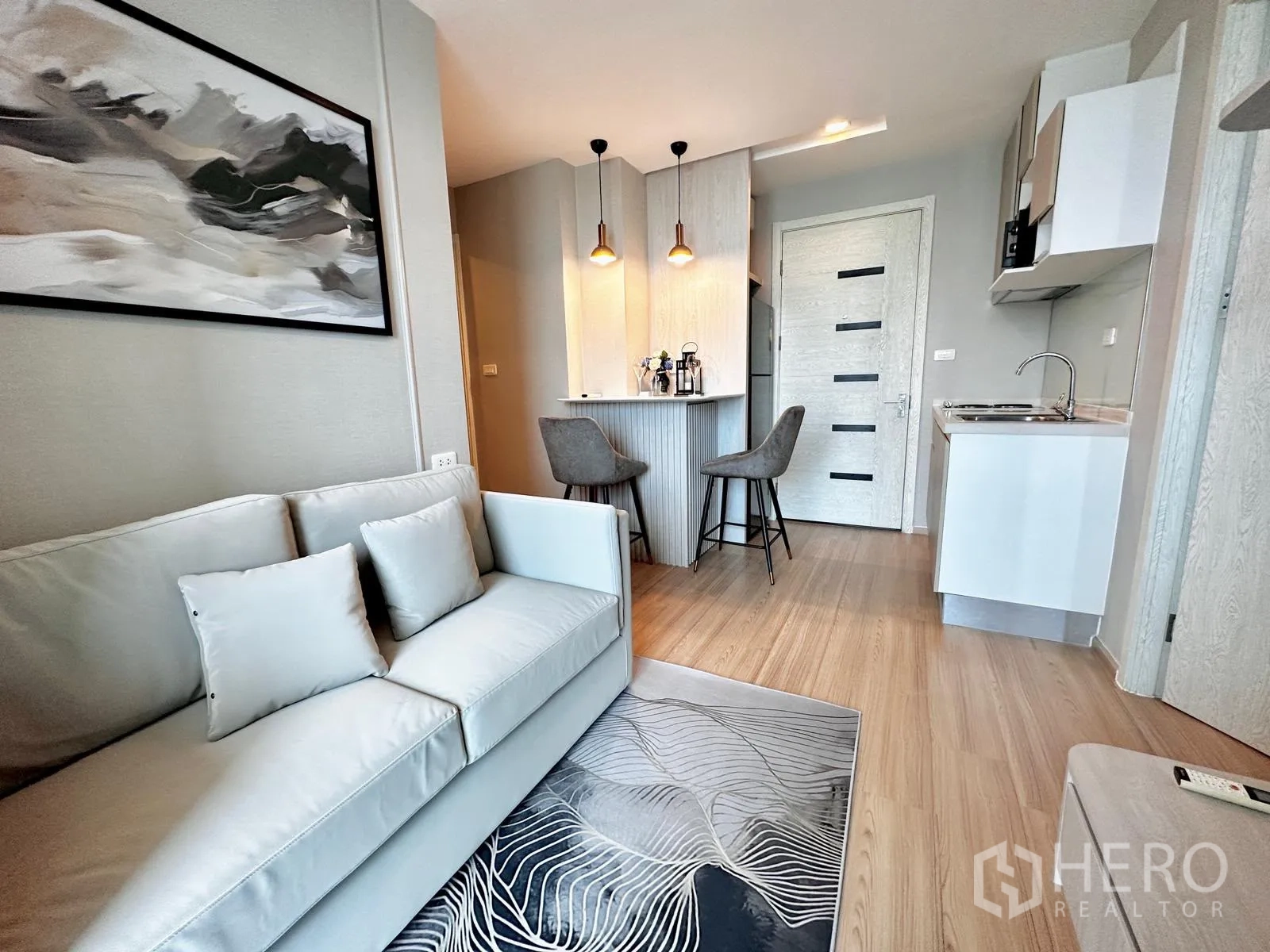 คอนโด for rent in Suan Luang, Bangkok - มุมห้องนั่งเล่นแสดงโซฟา ครัว และเคาน์เตอร์บาร์พร้อมสตูลสองตัว
