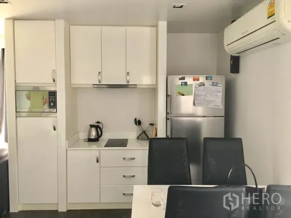 คอนโด ให้เช่าในWatthana, Bangkok - ครัวสีขาวบิลท์อินพร้อมตู้เก็บของ เตาไฟฟ้า ตู้เย็น และเก้าอี้รับประทานอาหาร