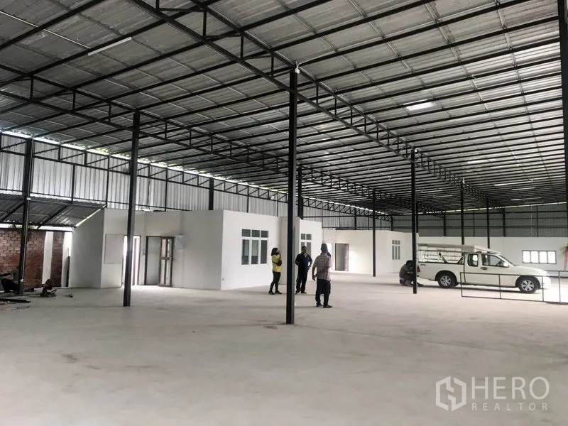 Warehouse for rent in Pathum Thani - Interior view showing built-in office rooms beneath a steel roof inside the warehouse.