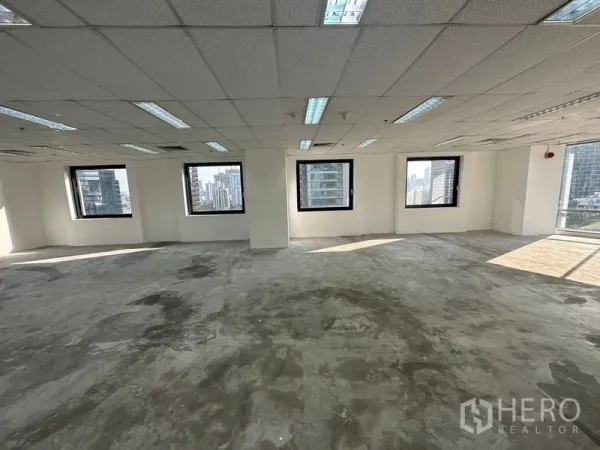 Office Space for rent - Spacious office floor plate with grid ceiling and four windows facing high-rise towers.