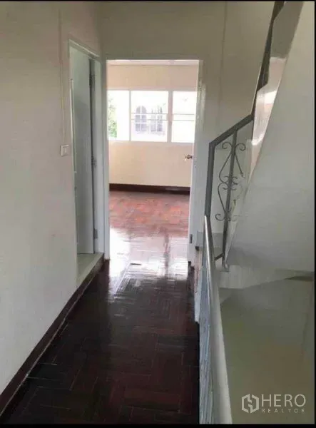 Home Office for rent or sale in Watthana, Bangkok - Upper hallway with dark parquet flooring and white walls leading to a sunlit room with windows.