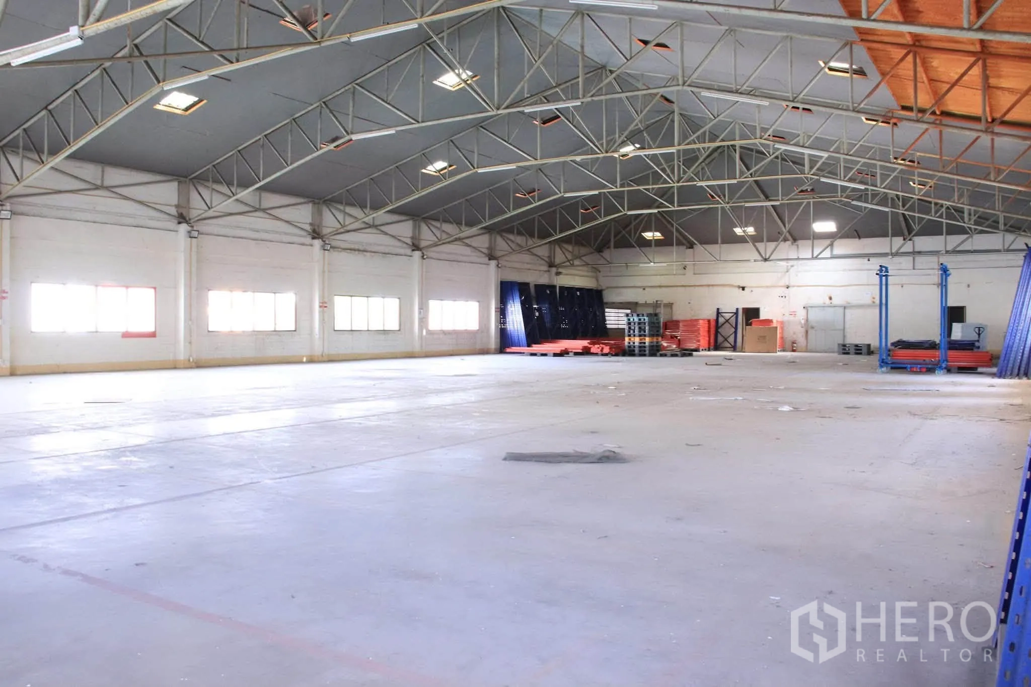 Warehouse for rent in Lat Phrao, Bangkok - Open warehouse floor with column-free span, industrial lighting, and racks and pallets along the walls.