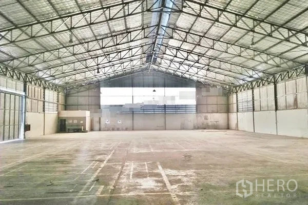 Warehouse for rent in Saphan Sung, Bangkok - Vast clear-span warehouse interior with high steel truss roof, skylights, and wide loading doors.