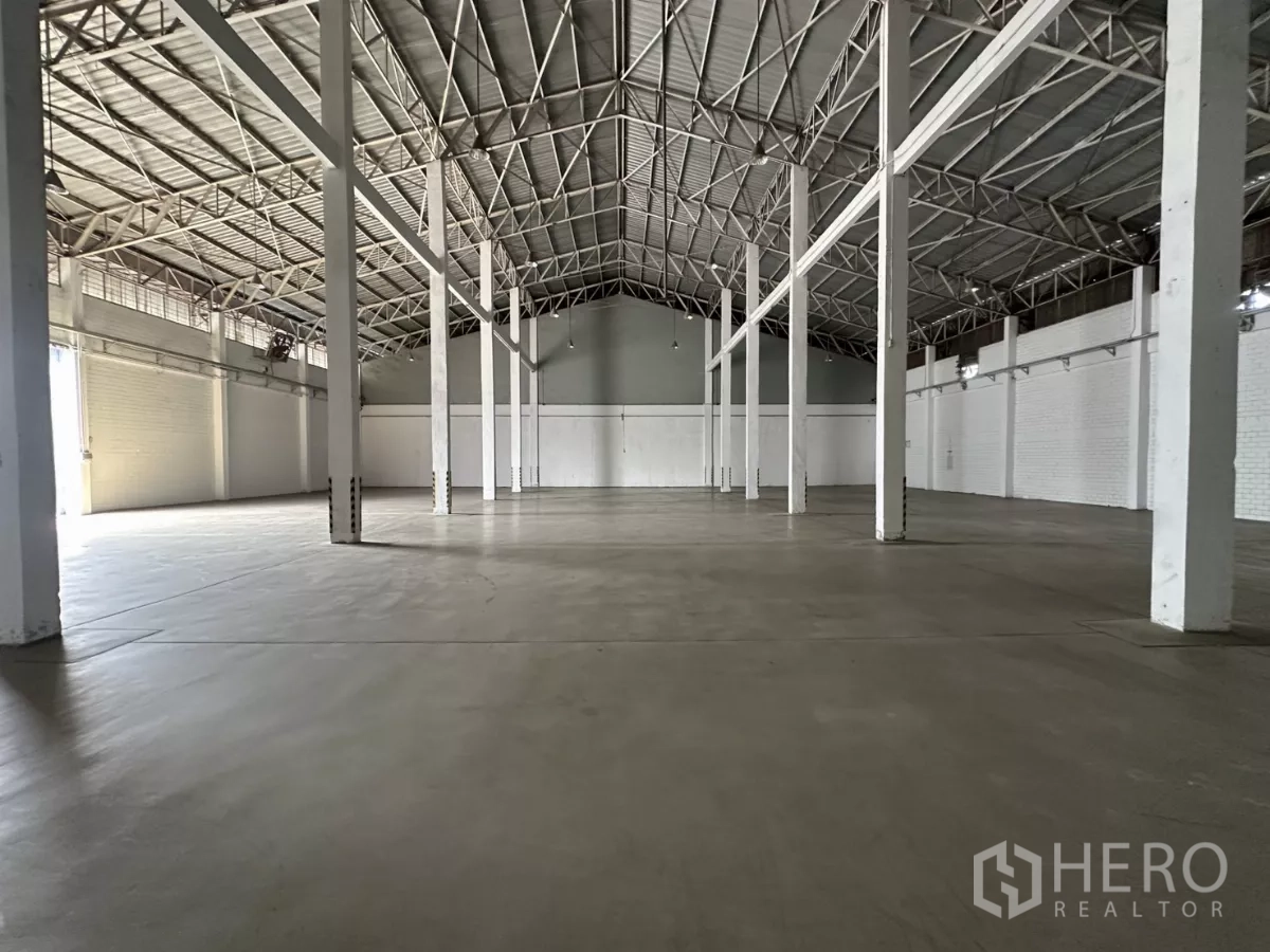 คลังสินค้า ให้เช่าในPhra Khanong, Bangkok - พื้นที่เก็บสินค้ากว้าง พื้นคอนกรีต เสาสีขาว และประตูโรลเลอร์ด้านท้าย