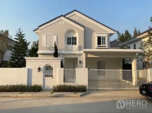 独立式住宅 出租在Bang Phli, Samut Prakan - 邦普里两层独立屋外观，白色立面、围栏大门与遮雨双车位车棚。