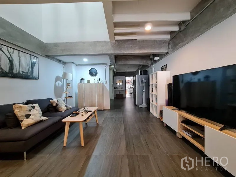 联排别墅 出租在Khlong Toei, Bangkok - 宽敞客厅，沙发、大屏电视与工业风天花