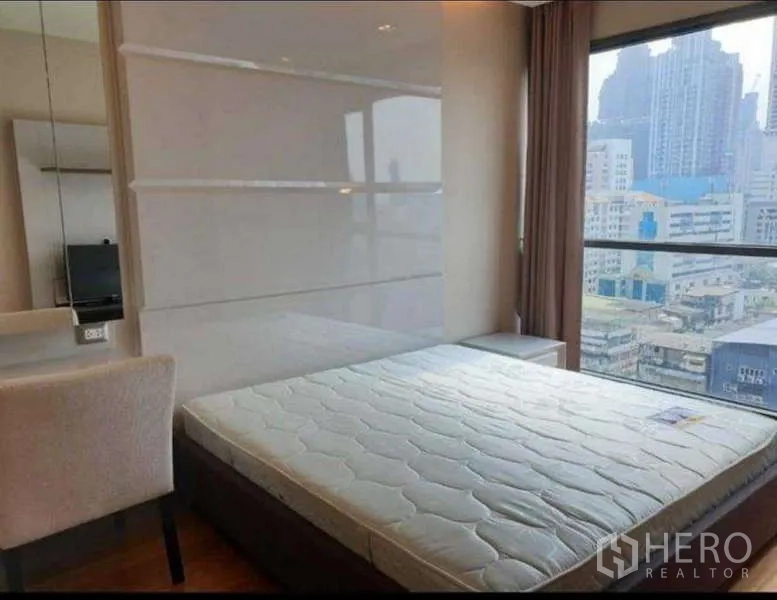 Condominium for rent in Bang Rak, Bangkok - Sunlit bedroom with queen mattress, dressing table and panoramic Bangkok skyline view.