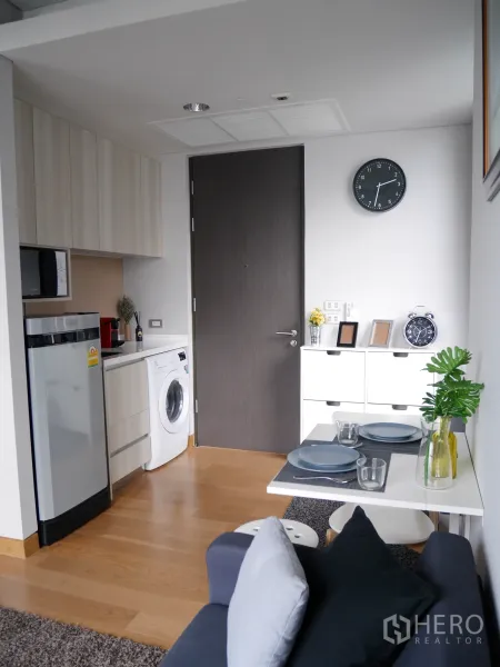 Condominium for rent in Khlong Toei, Bangkok - Smart kitchenette with refrigerator, microwave, in-unit washing machine, and warm wood flooring.