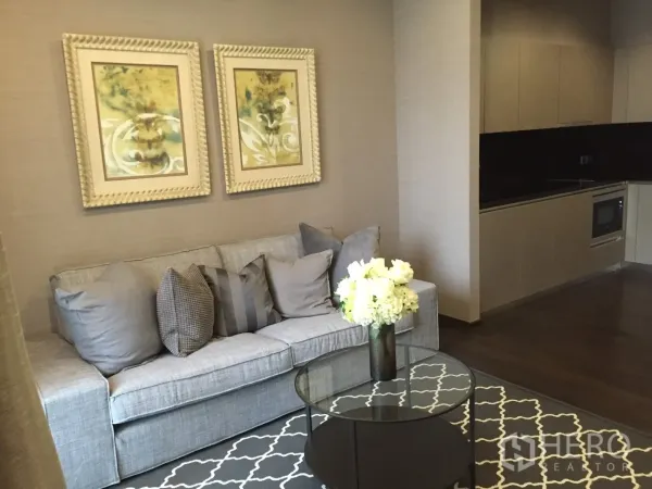 公寓 出租在Watthana, Bangkok - 素坤逸39公寓的开放式起居区，灰色沙发、玻璃茶几与现代一体化厨房。