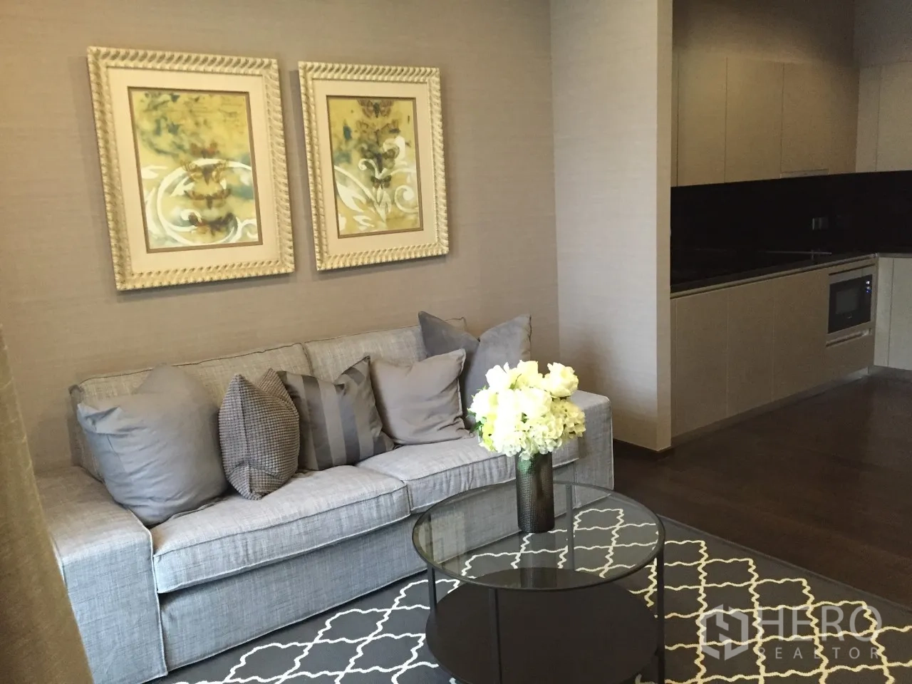 公寓 出租在Watthana, Bangkok - 素坤逸39公寓的开放式起居区，灰色沙发、玻璃茶几与现代一体化厨房。