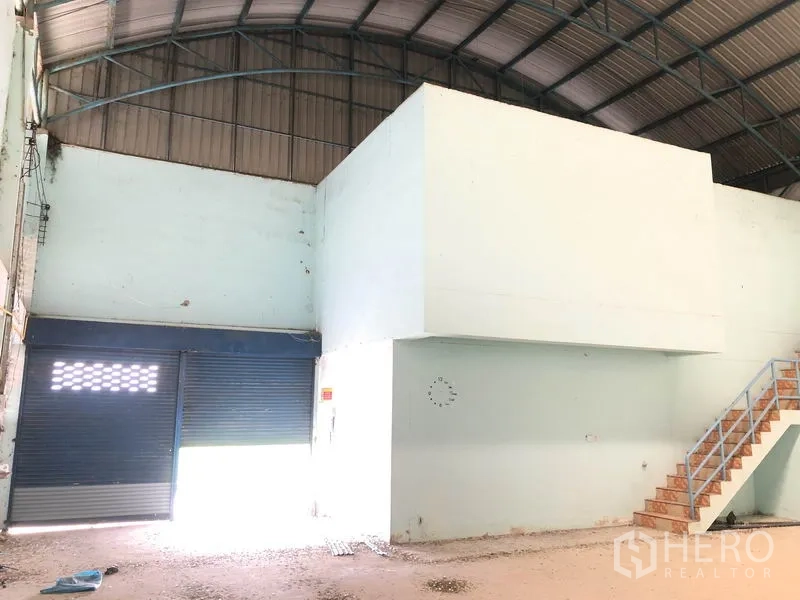 Warehouse for rent in Nonthaburi - Large roller shutter loading doors and box mezzanine room beneath arched roof.