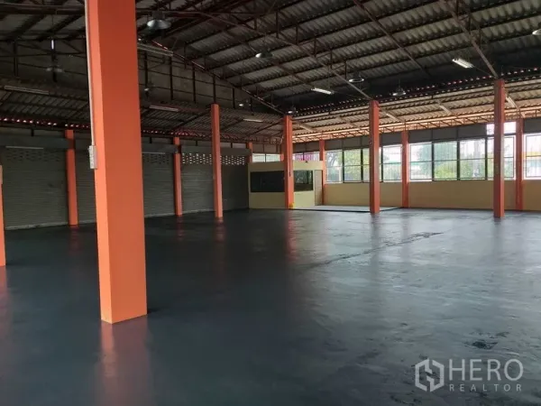 货栈 出租在Khlong Sam Wa, Bangkok - 开放式仓库大厅，多根橙色柱、大片窗与卷帘门。