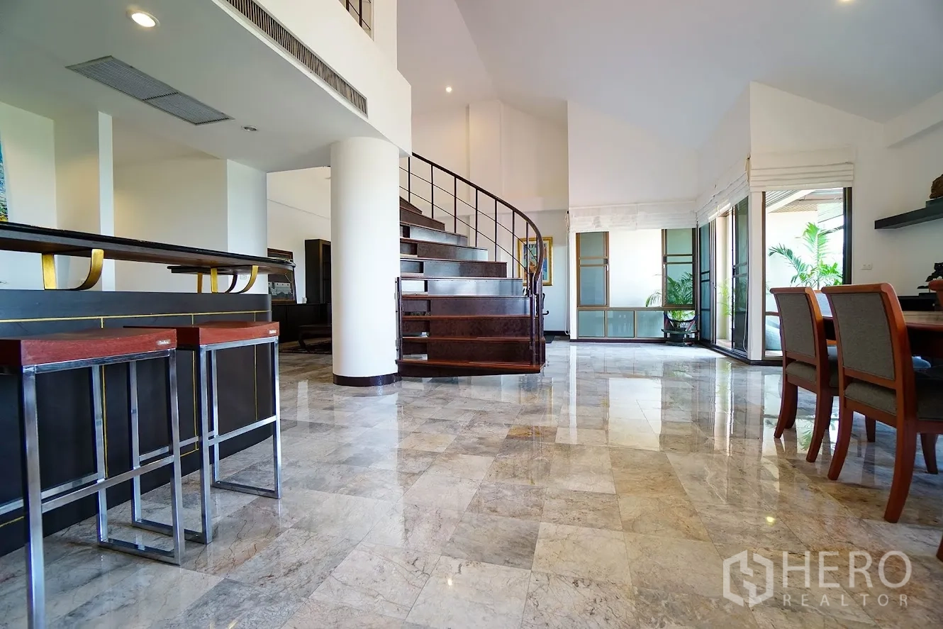 房间 出租在Watthana, Bangkok - 低角度拍摄的弧形木楼梯，旁有吧台与落地窗。