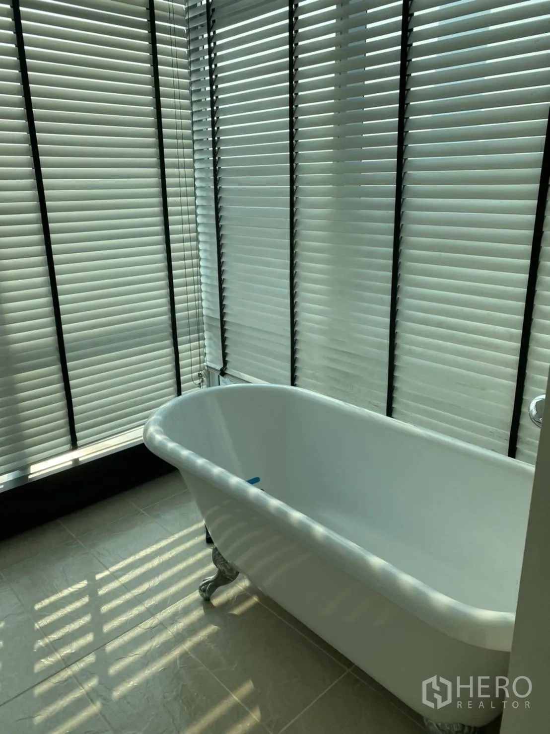 คอนโด ให้เช่าในKhlong San, Bangkok - ภาพระยะใกล้อ่างอาบน้ำขาตั้งสีขาว ข้างมู่ลี่หน้าต่างสูงและแสงแดด