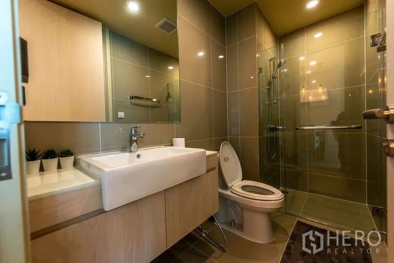Condominium for rent in Watthana, Bangkok - Modern bathroom with glass-enclosed shower, vanity and neutral tile finishes.