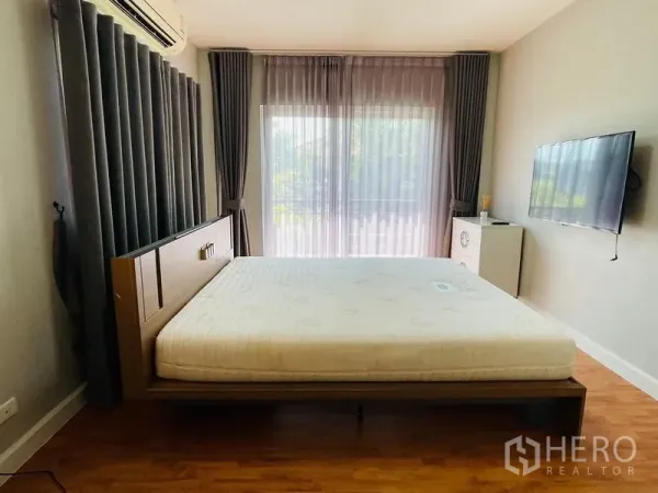 บ้าน ขายในLam Luk Ka, Pathum Thani - ห้องนอนติดแอร์ มีประตูกระจกออกระเบียง ผ้าม่านสีเทา และทีวีแขวนผนัง