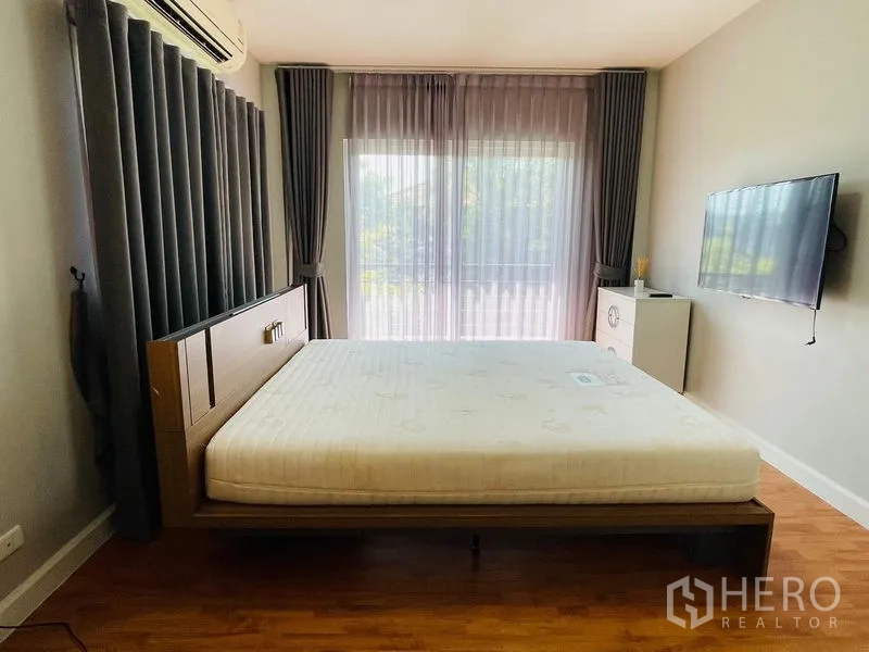 บ้าน ขายในLam Luk Ka, Pathum Thani - ห้องนอนติดแอร์ มีประตูกระจกออกระเบียง ผ้าม่านสีเทา และทีวีแขวนผนัง