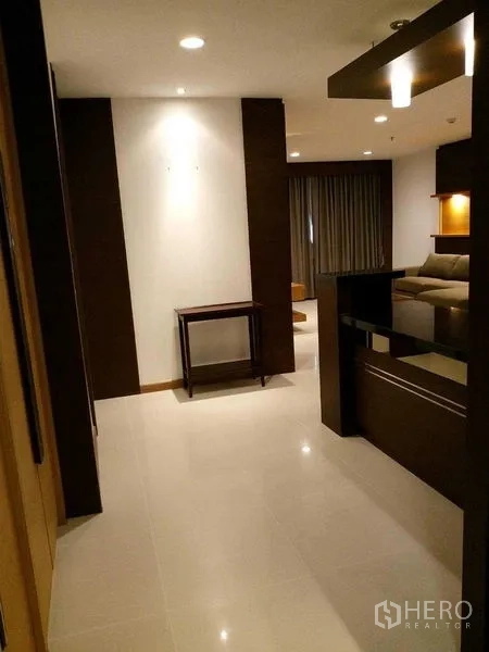 Condominium for rent in Sathon, Bangkok - Entry hallway leading to the lounge with glossy tile floors, dark wood accents, and recessed lights.