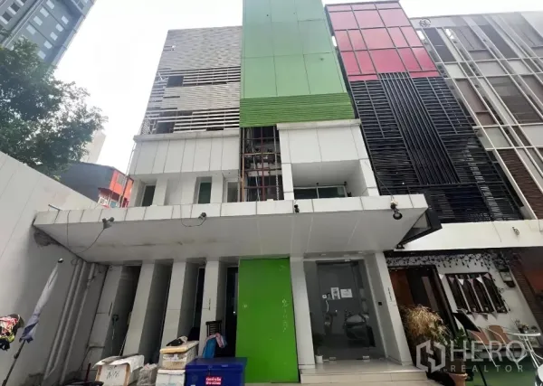 店屋 出售在Watthana, Bangkok - 位于黄金地段的多层商铺楼外立面，绿色面板与玻璃入口。