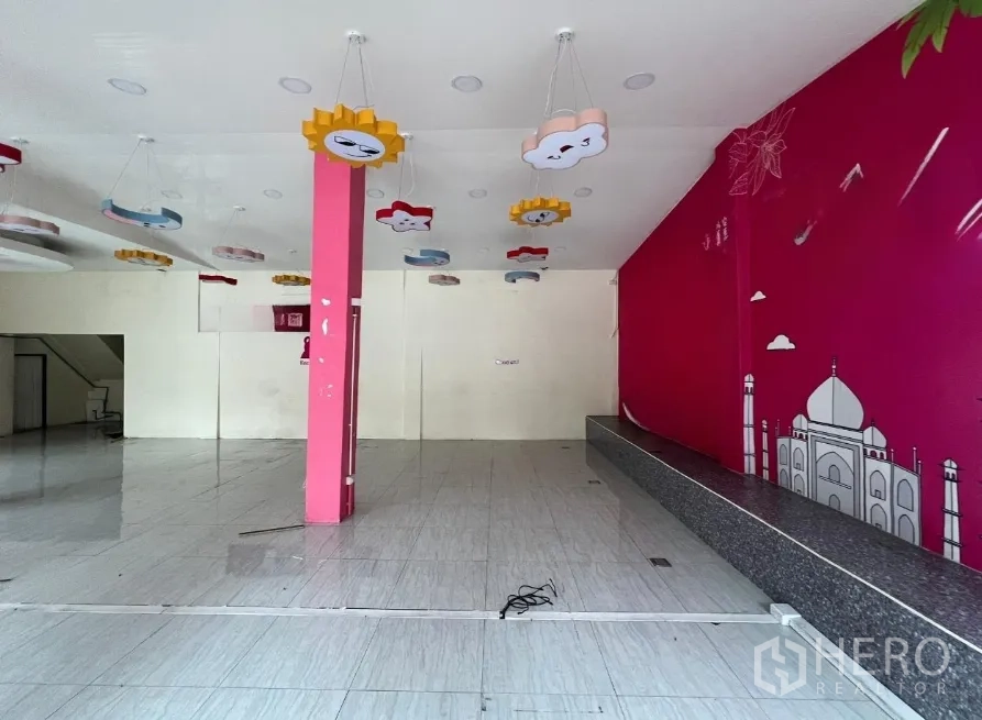 店屋 出租在Watthana, Bangkok - 开阔的零售空间，瓷砖地面，粉色主题墙与云朵阳光吊灯。