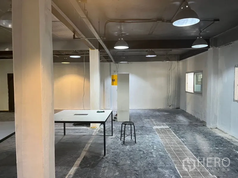 零售空间 出租在Pathum Wan, Bangkok - 毛坯零售楼层，照明、走线与中央桌。