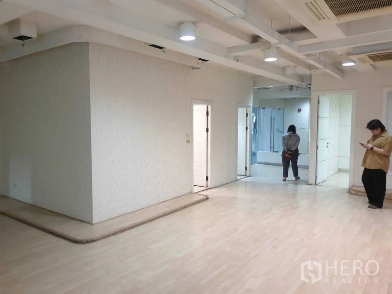 Office Space for rent - Open-plan office area with light flooring, exposed ceiling beams and partitioned rooms.