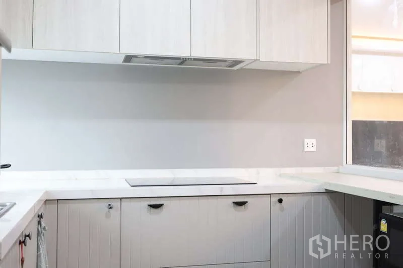 Detached House for rent or sale in Prawet, Bangkok - Close-up of the modern cooktop, marble-look counters and overhead wall cabinets.