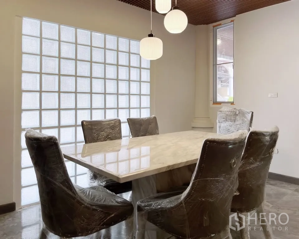 Home Office for rent in Watthana, Bangkok - Dining area with a marble table and six chairs beside a glass-block feature wall.