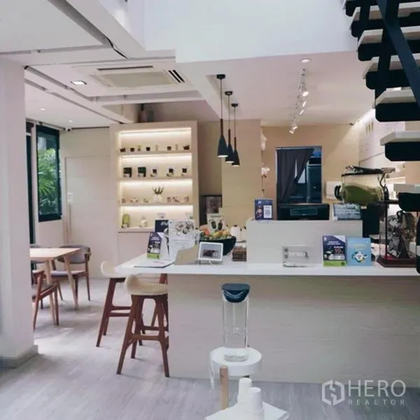 店屋 出租在Bang Rak, Bangkok - 明亮的咖啡吧台与陈列架，吊灯及通往夹层的楼梯，位于Silom商铺。