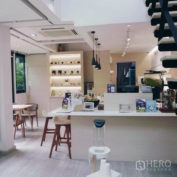 店屋 出租在Bang Rak, Bangkok - 明亮的咖啡吧台与陈列架，吊灯及通往夹层的楼梯，位于Silom商铺。