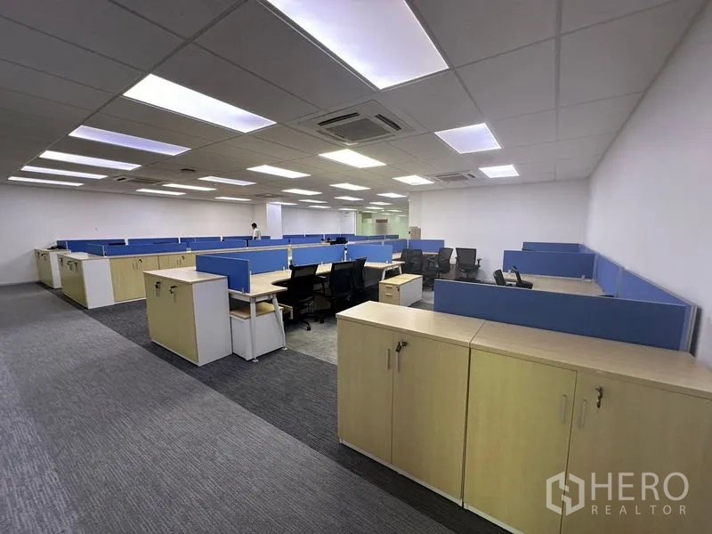 Office Space for rent - Open office area featuring rows of blue-partition desks, storage cabinets and bright LED lighting.