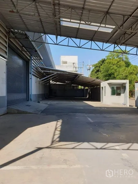 คลังสินค้า ให้เช่าในLam Luk Ka, Pathum Thani - ลานโหลดคลุมหลังคา มีประตูม้วนและป้อมยามบนพื้นคอนกรีต
