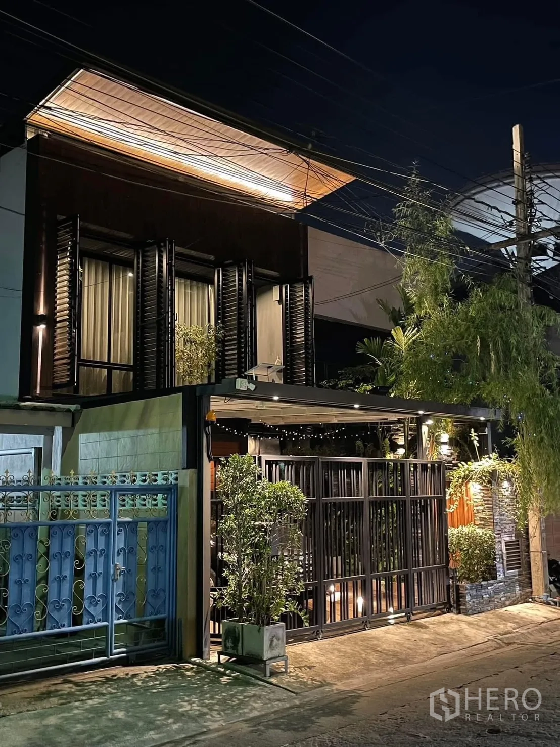 Home Office for rent or sale in Bang Kapi, Bangkok - Contemporary two-storey home office facade at night with gated carport, warm lighting and lush greenery in Bang Kapi.