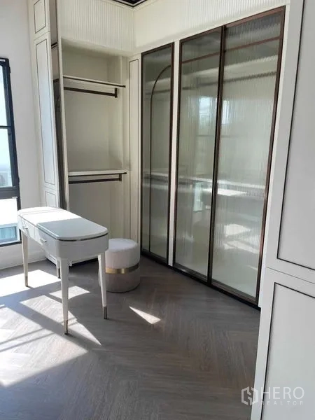 Detached House for sale in Saphan Sung, Bangkok - Walk‑in closet with glass wardrobes and a dressing table lit by natural light.