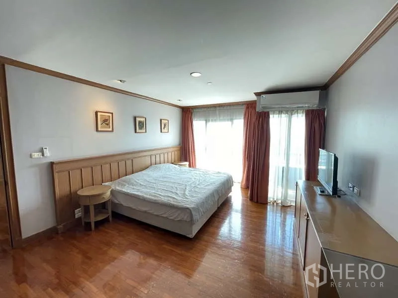 คอนโด ให้เช่า - ห้องนอนพร้อมหัวเตียงไม้ ชั้นวางทีวี และประตูระเบียงพร้อมผ้าม่าน