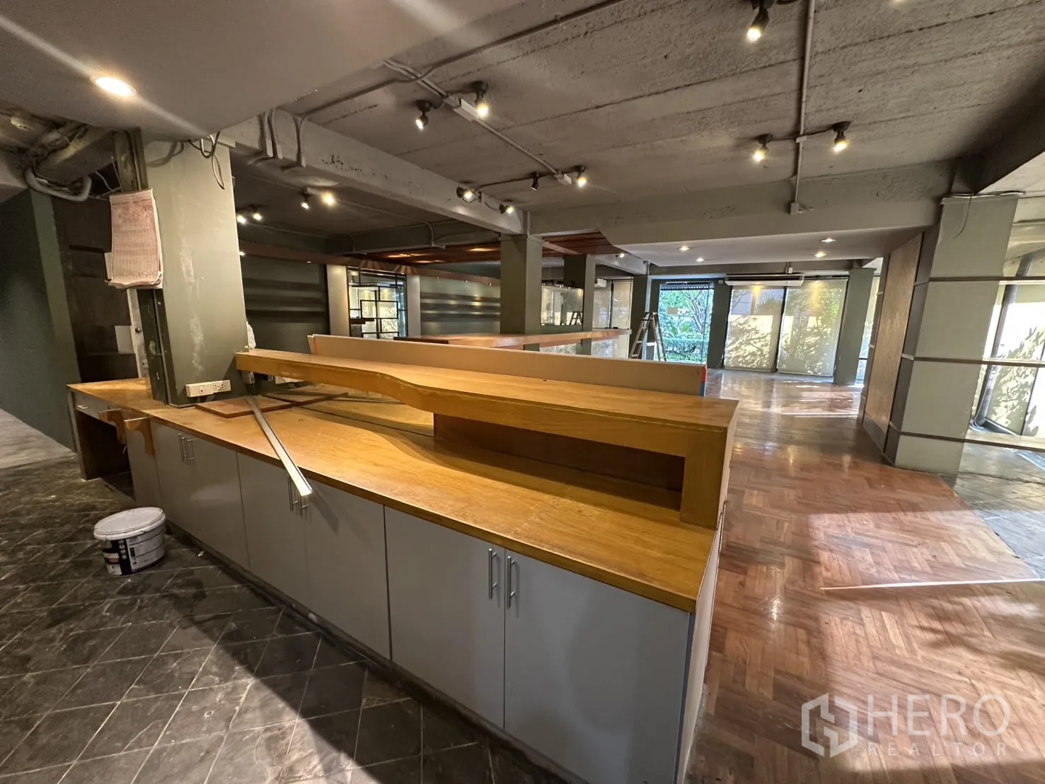 Retail Space for rent in Watthana, Bangkok - Built‑in wooden bar with base cabinets in a spacious showroom with mixed flooring.