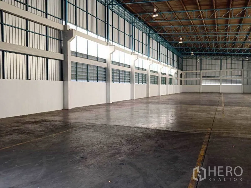 工厂 出租在Samut Prakan - 侧墙视角，可见百叶通风窗与无柱大空间地面。