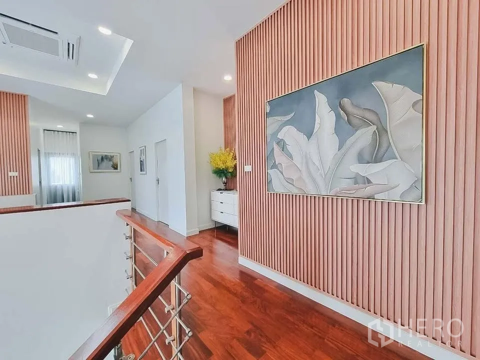 Detached House for rent or sale in Bang Phli, Samut Prakan - Upper hallway with wooden slat wall, artwork, and stair railing.