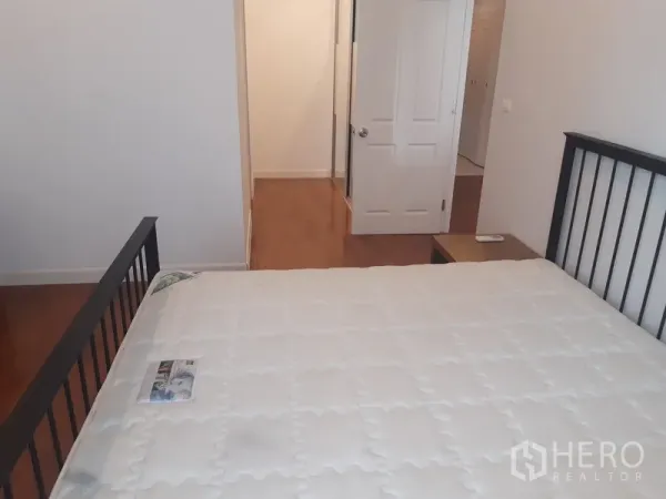 คอนโด ให้เช่าในKhlong Toei, Bangkok - มุมมองห้องนอนหลักไปยังประตูทางเข้า พื้นไม้ และโต๊ะหัวเตียง