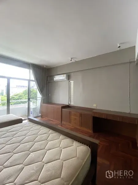 公寓 出租在Sathon, Bangkok - 宽敞卧室配长书桌与矮柜，壁挂空调，推拉门连接阳台。