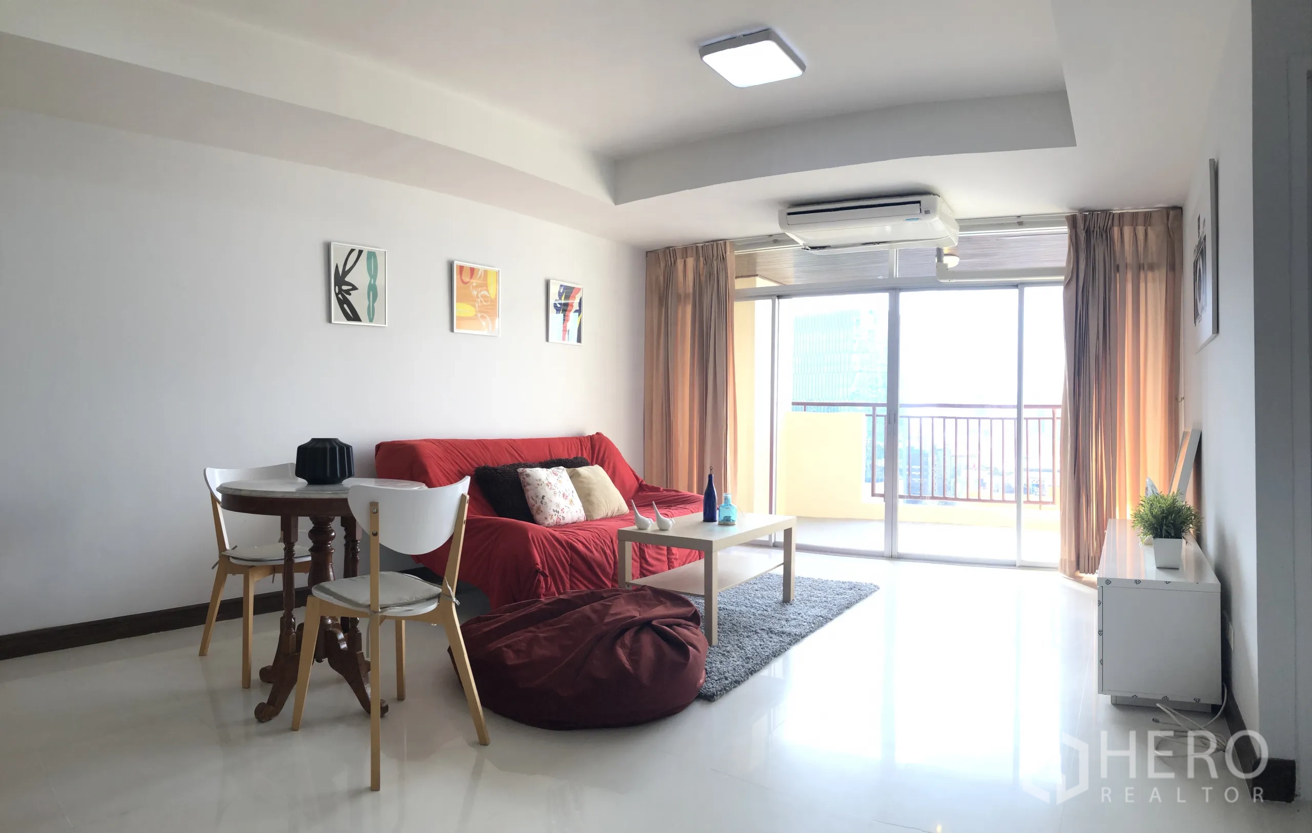 คอนโด ให้เช่าหรือขายในKhlong Toei, Bangkok - ห้องรับแขกกว้าง ติดภาพบนผนัง โซฟาสีแดง บีนแบ็ค และกระจกเต็มบานเปิดสู่ระเบียง