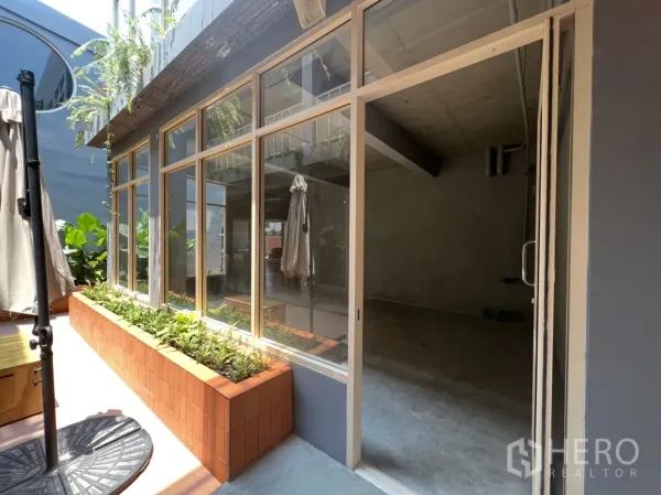 零售空间 出租在Watthana, Bangkok - 店铺入口特写，落地玻璃门与砖砌花坛相邻的露台