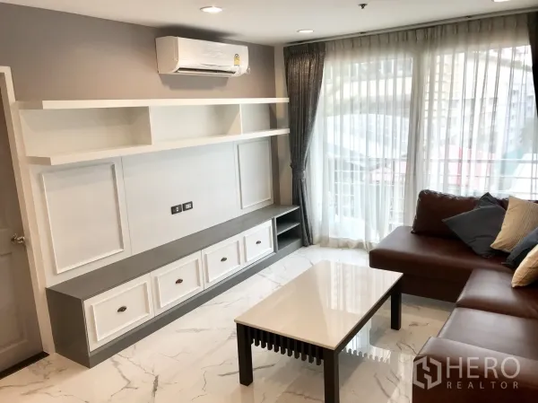 公寓 出租或出售在Khlong Toei, Bangkok - 内置电视柜与开放搁架，空调与大窗旁的沙发。