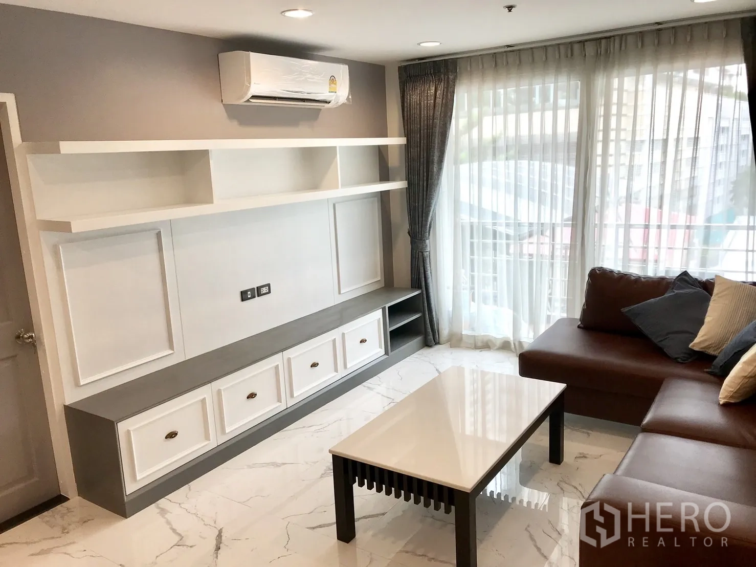 公寓 出租或出售在Khlong Toei, Bangkok - 内置电视柜与开放搁架，空调与大窗旁的沙发。