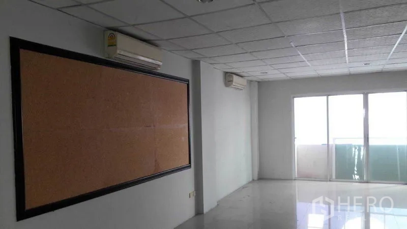 Office Space for rent in Bueng Kum, Bangkok - Bright office room with cork board, drop ceiling and sliding glass doors to a balcony.