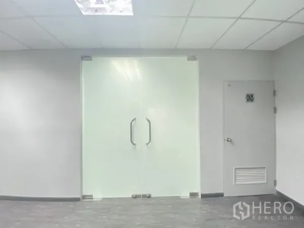 办公空间 出租在Chatuchak, Bangkok - 磨砂玻璃双开门与服务门特写，灰色地面走廊。