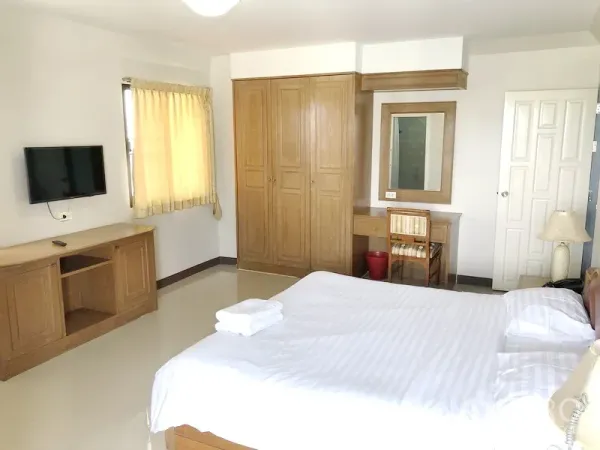 Apartment for rent in Suan Luang, Bangkok - Spacious bedroom with king bed, wooden wardrobe, vanity desk and wall-mounted TV.
