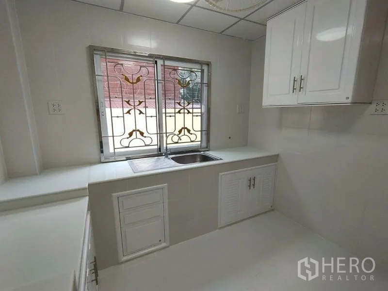 บ้าน ให้เช่าในKhlong Toei, Bangkok - ครัวบิลท์อินโทนขาว อ่างล้างจาน ตู้เก็บของ และเหล็กดัดหน้าต่างลวดลาย