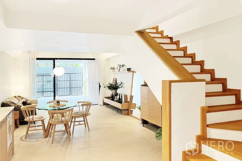 联排别墅 出租在Khlong Toei, Bangkok - 一层客餐厅配木质楼梯与大幅推拉门通向前庭。