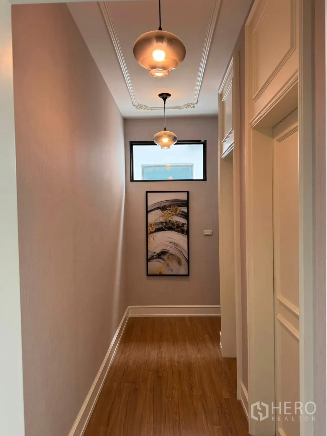 Townhouse for rent in Lat Phrao, Bangkok - Hallway with pendant lights, artwork and wood flooring.